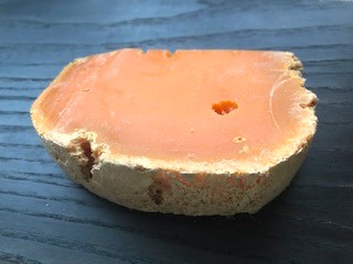 (18~24か月熟成のエクストラ・ヴィエイユ・ミモレット。粉っぽい外皮と所々に見られる穴はコナダニが作りだします。この穴からチーズが呼吸をして、周囲の水分を吸収します。コナダニはミモレットの熟成に重要な働きをします。若いミモレットのマイルドな味わいは熟成が進むごとに濃厚になり、ヴィエイユ・ミモレットの風味はからすみに例えられます。)