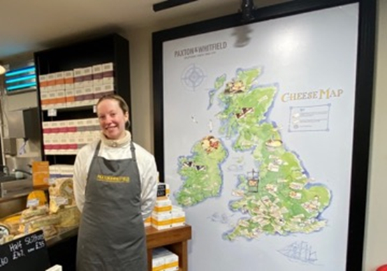 笑顔の秘密はチーズ!?店内入り口のチーズマップとともにポーズをとってくれた、とても親切な店員さん。