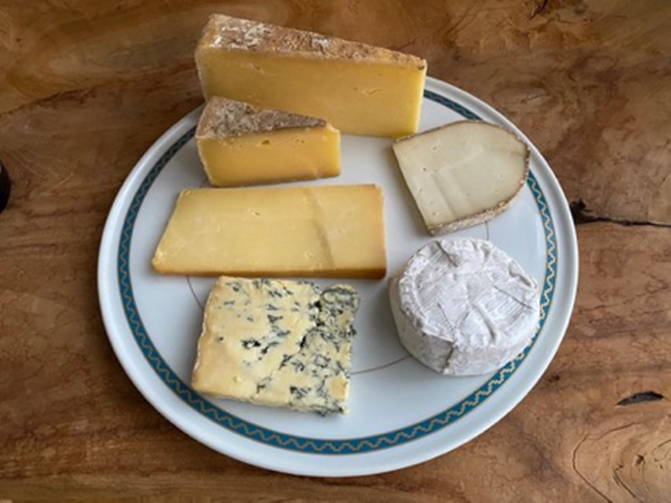 上から時計回りで: 伝統的な布巻き製法で作られたチェダーのピッチフォーク、山羊のミルクを使った珍しいセミハードタイプのレイチェル、「ワールド・チーズ・アワード 2023/24」で受賞を果たした羊乳白カビタイプのウィグモア、まさに格別な逸品スティルトン、深みのあるスモーキーな風味のウェストコム・スモーク・チェダー、パックス&ウィットフィールドのために特別に手作りされているウォッシュタイプのコリニウム。